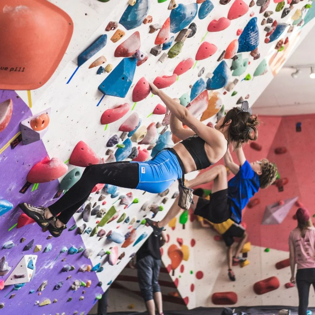 A climber sending on the colourful comp wall as the crowd watches