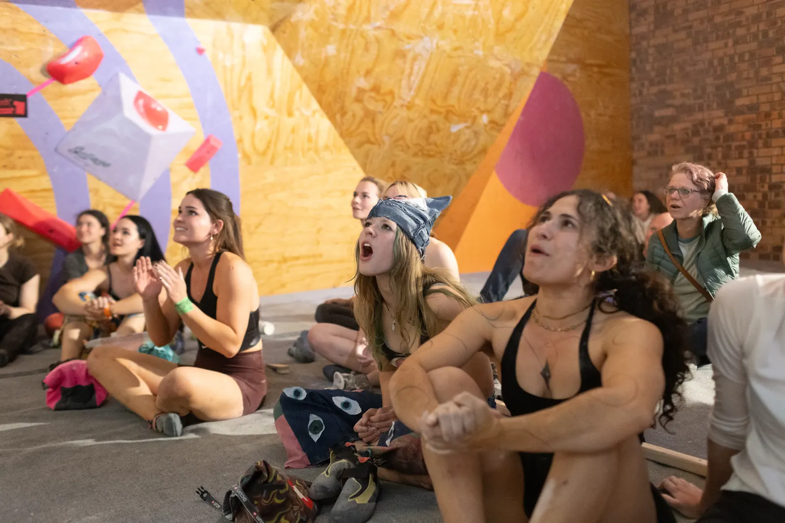 The crowd sitting on the mats, cheering a climber on