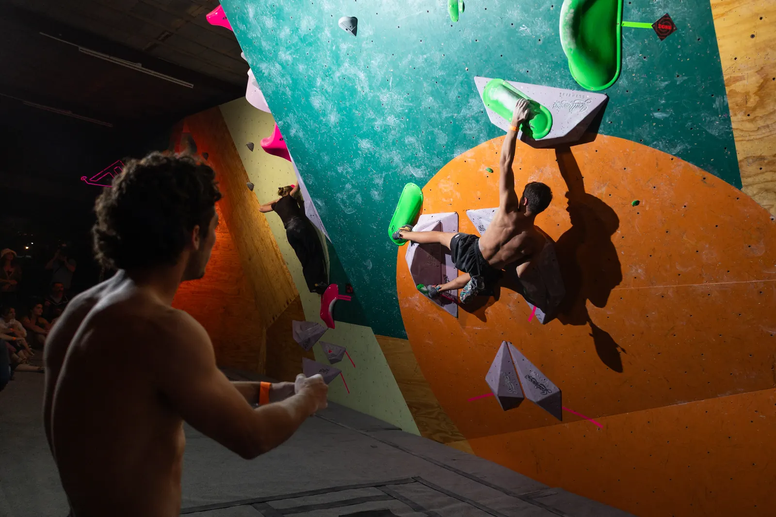 A climber on the wall while a teammate watches from below